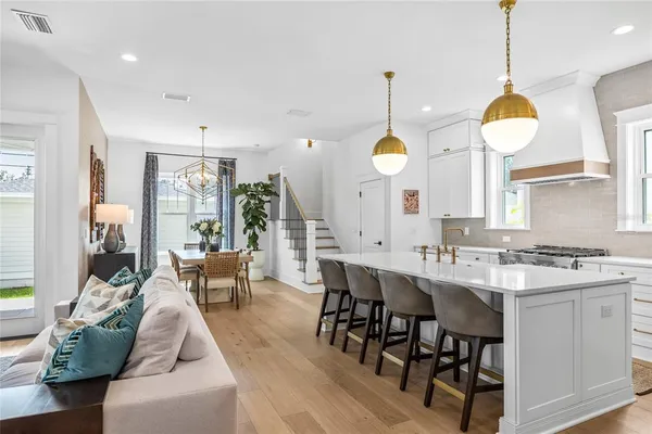 a kitchen with stainless steel appliances granite countertop a stove a sink a living room with couches chairs and couches with wooden floor