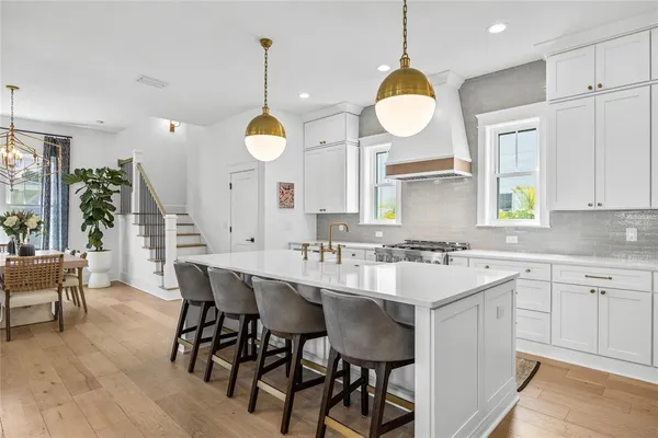 a kitchen with a dining table cabinets stainless steel appliances and wooden floor