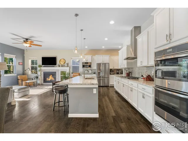 a kitchen with stainless steel appliances granite countertop a stove a sink dishwasher and white cabinets with wooden floor