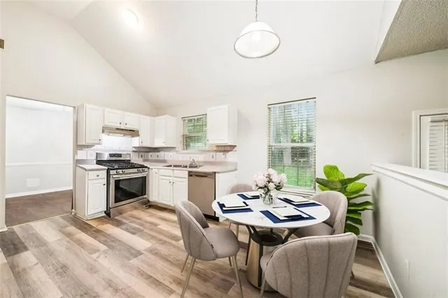 a kitchen with a table chairs stove and white kitchen