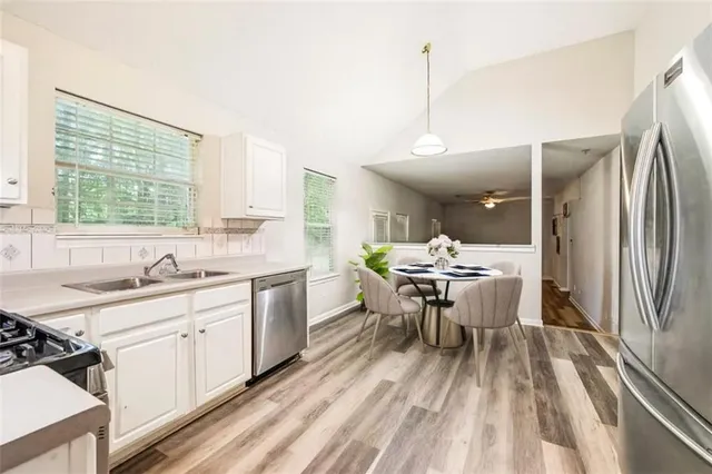 a kitchen with a sink dishwasher a dining table and chairs with wooden floor