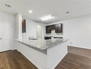 a view of a kitchen with stainless steel appliances granite countertop a sink and a wooden floor