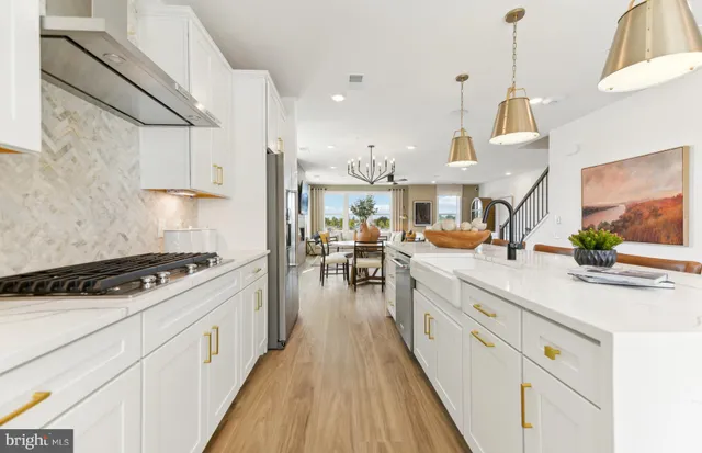 a kitchen with stainless steel appliances a dining table chairs a refrigerator and cabinets