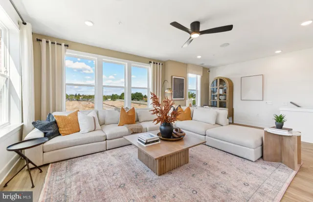 a living room with furniture ceiling fan and a large window