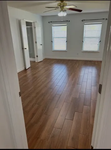 a view of an empty room with wooden floor and a window
