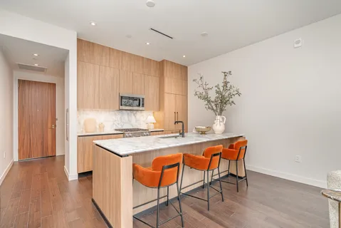 a kitchen with stainless steel appliances granite countertop a stove top oven a sink and white cabinets with wooden floor