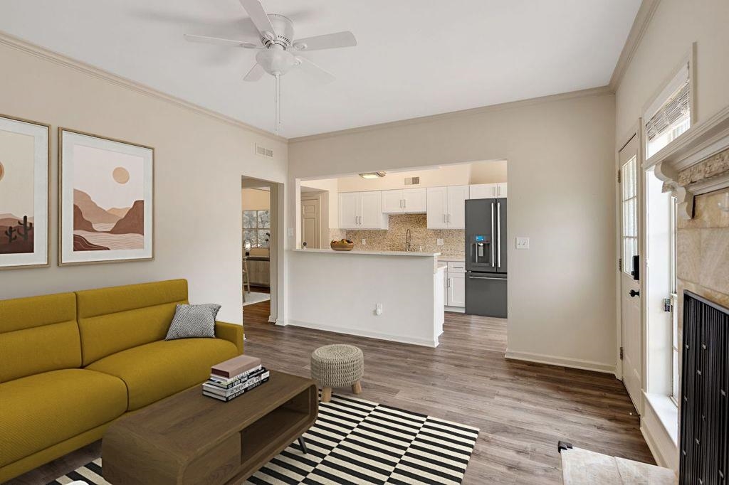Living room with wood finished floors, crown molding, and ceiling fan