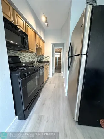 a view of a kitchen with an empty space and wooden floor