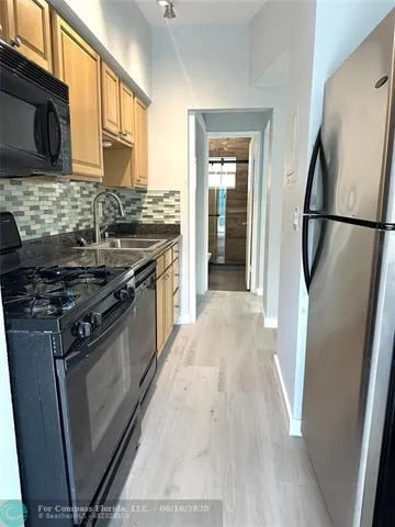 a kitchen with stainless steel appliances granite countertop a refrigerator a stove and a sink