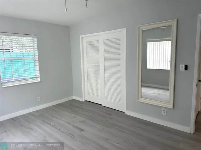 an empty room with wooden floor closet and windows