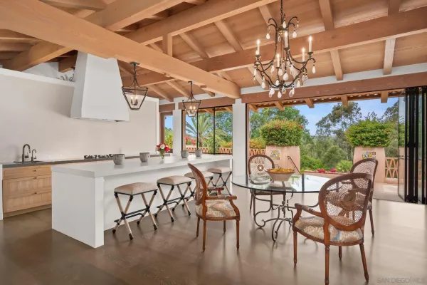 a view of a dining room with furniture a chandelier and large windows