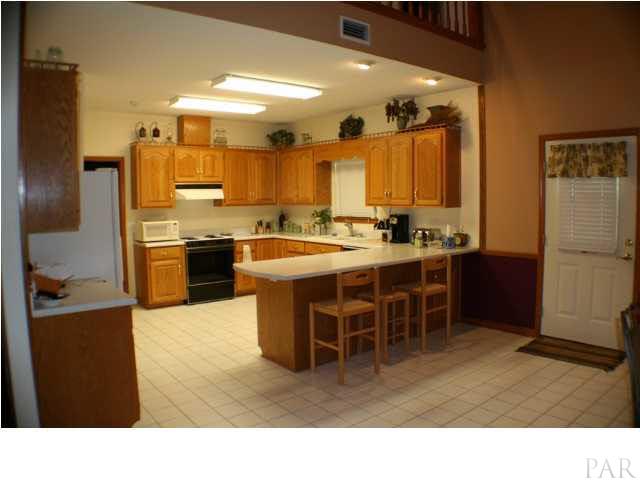 6012 Saddle Club Road Pace, FL 32571 - Photo 9 of 24 Large inviting kitchen with an abundance of cabinetry ~ Multiple work spaces and pantry. Formla dining room is throgh the kitchen on the front of the home.
