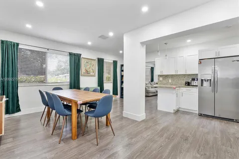 a kitchen with stainless steel appliances granite countertop a stove a refrigerator a kitchen island a dining table and chairs