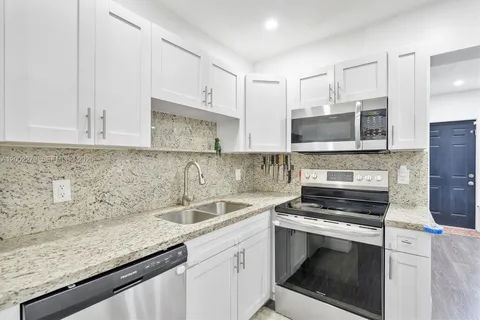 a kitchen with granite countertop a sink stove and microwave