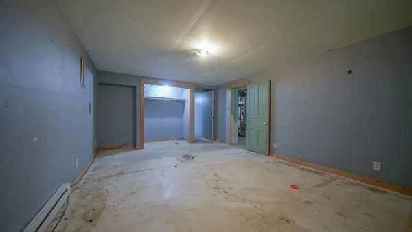 an empty room with wooden floor cabinet and windows