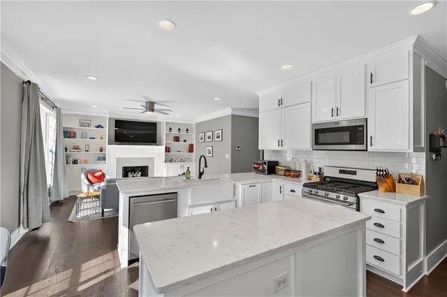 a kitchen with stainless steel appliances a stove top oven a sink a refrigerator white cabinets and wooden floor