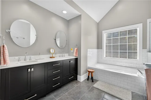 a spacious bathroom with a double vanity sink mirror and a bathtub