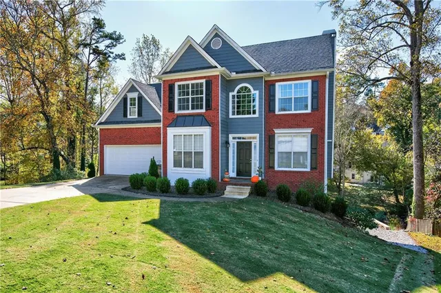 a front view of a house with a yard and trees