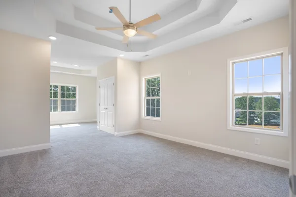 an empty room with a ceiling fan and windows