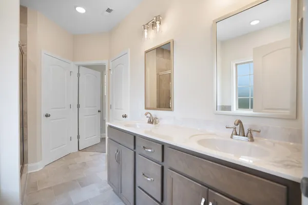 a bathroom with a sink double vanity granite tub shower and a mirror