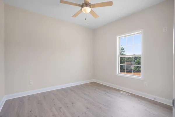 an empty room with a window and a ceiling fan