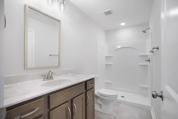 a bathroom with a granite countertop sink a toilet and shower