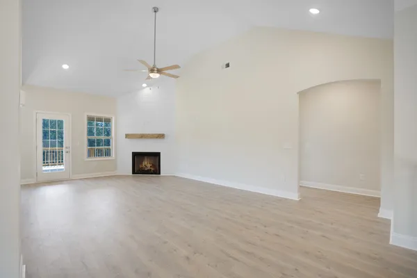 an empty room with chandelier fan and fireplace