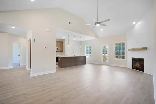 an empty room with wooden floor fireplace and windows