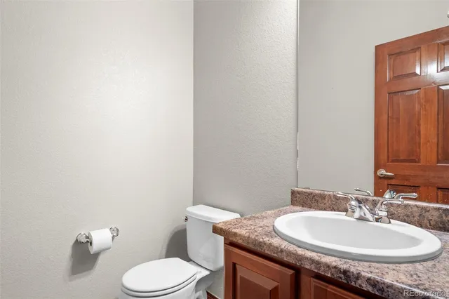 a bathroom with a granite countertop sink a toilet and a mirror