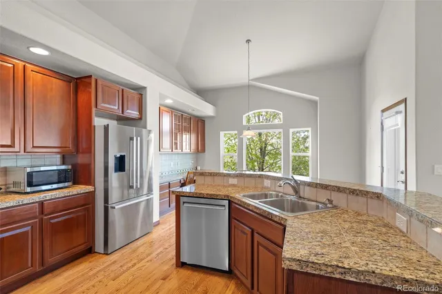 a kitchen with granite countertop a sink stainless steel appliances and windows