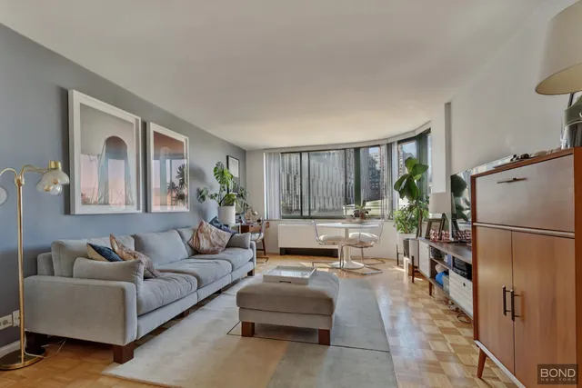 a living room with furniture and a refrigerator