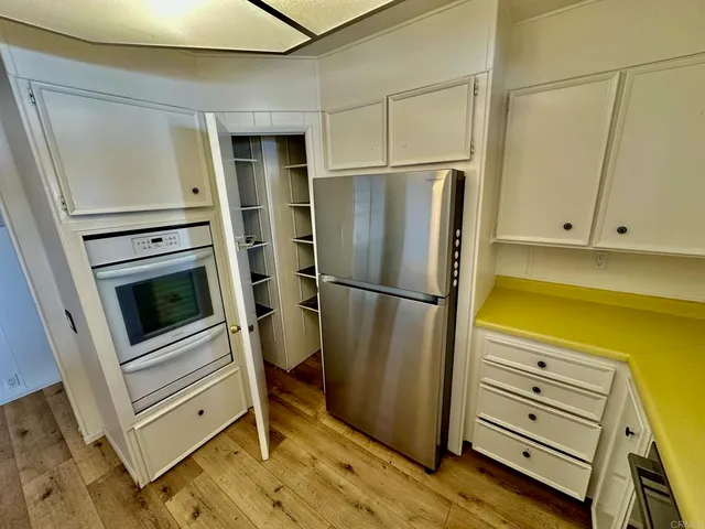 a view of a refrigerator in kitchen and an empty room