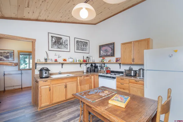 a view of a dining room with furniture a kitchen and chandelier
