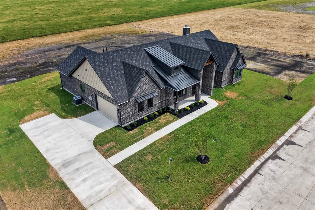 5410 Sunset Road Caddo Mills, TX 75135 - Photo 7 of 40 Brick exterior with a prominent front entrance, multiple roof planes, a two-car garage, an expansive concrete driveway, and a manicured lawn