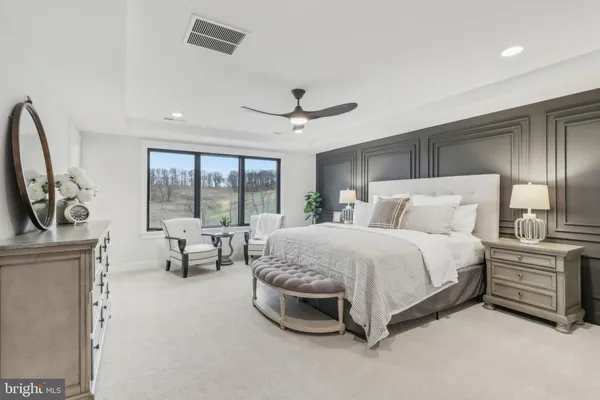 a spacious bedroom with a bed a table and large mirror