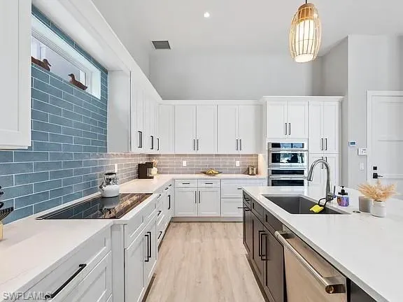 a kitchen with a sink dishwasher stove and white cabinets with wooden floor