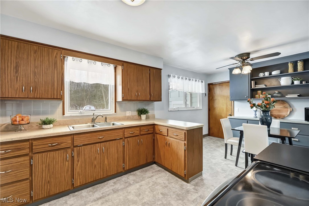 Kitchen with ceiling fan, decorative backsplash, sink, and kitchen peninsula