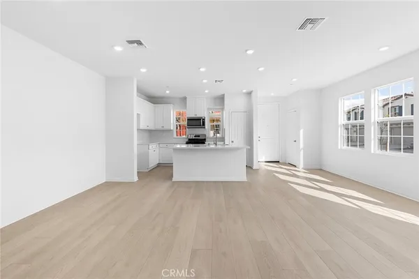 a view of a kitchen with center island stainless steel appliances wooden floor cabinets and a window