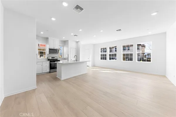 a view of an empty room with kitchen and window