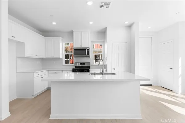 a kitchen with kitchen island a white counter top space cabinets and stainless steel appliances
