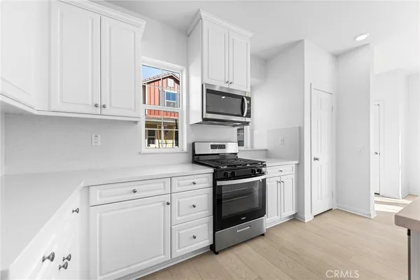a kitchen with cabinets stainless steel appliances and wooden floor
