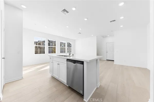 a view of a kitchen with a sink and dishwasher a refrigerator with wooden floor