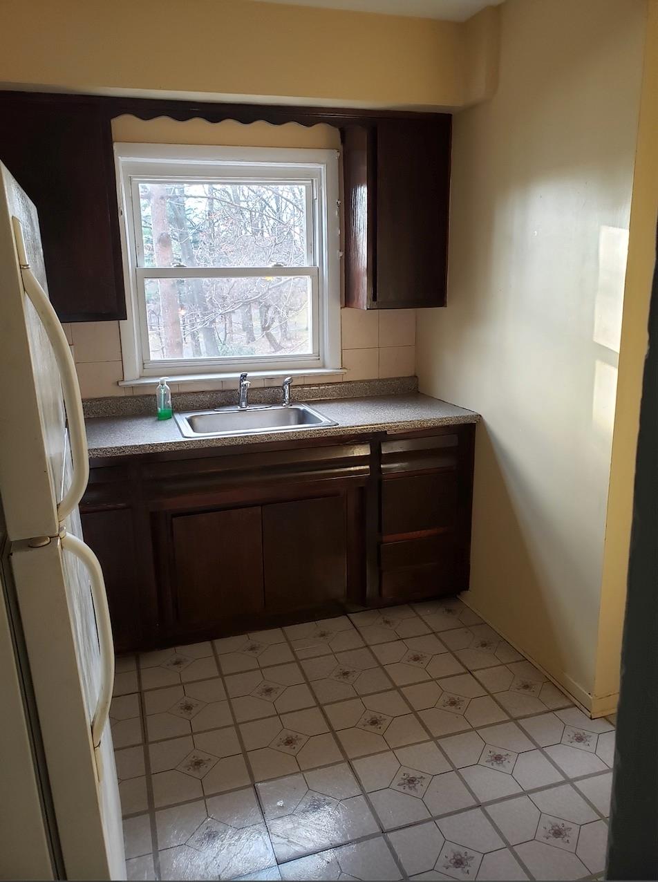 166-26 Gothic Drive, Unit 2 Queens, NY 11432 - Photo 10 of 10 Kitchen featuring dark brown cabinets, decorative backsplash, freestanding refrigerator, and a sink
