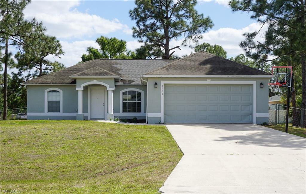 3703 Sunset Road Lehigh Acres, FL 33971 - Photo 1 of 12 a front view of a house with a yard and garage