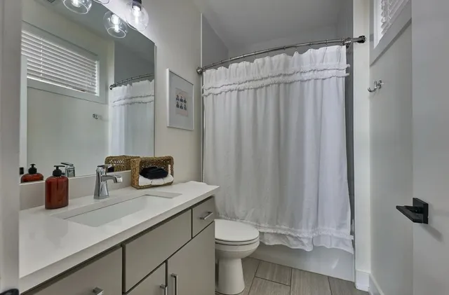 a bathroom with a sink a toilet and shower curtain