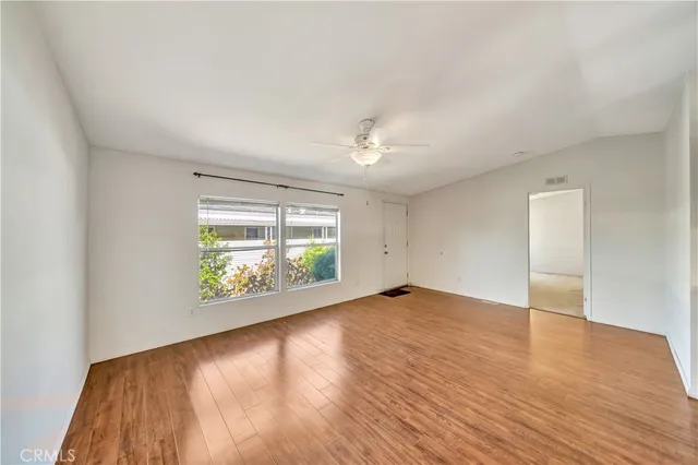 a view of an empty room with window and wooden floor