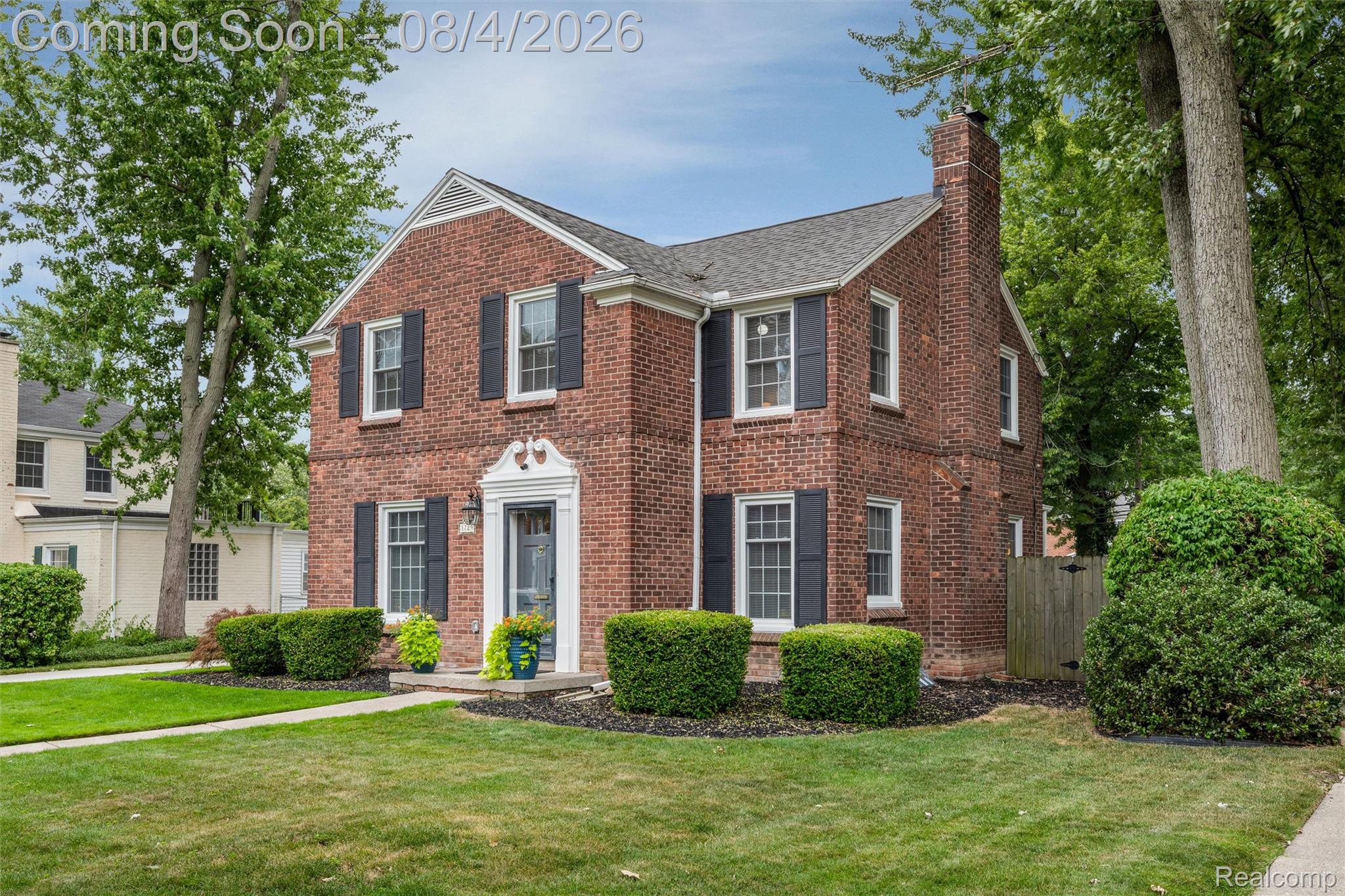 1729 Broadstone Road Grosse Pointe, MI 48236 - Photo 6 of 39 Traditional brick home featuring a prominent chimney, dark shutters, an ornate front entry, mature trees, and manicured landscaping