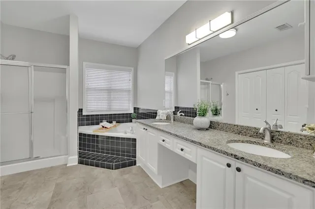 a bathroom with a granite countertop double vanity sink and mirror
