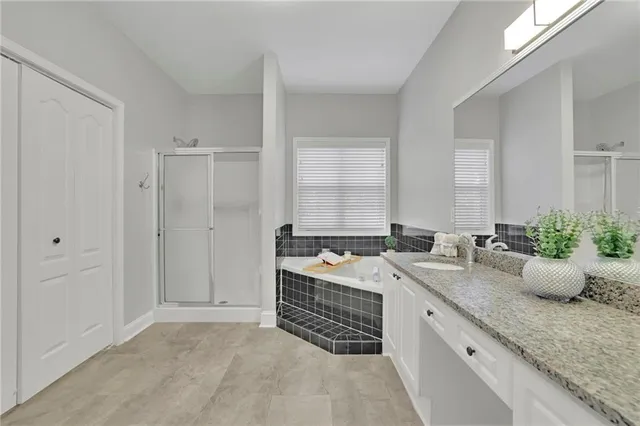 a spacious bathroom with a granite countertop sink a mirror and a bathtub