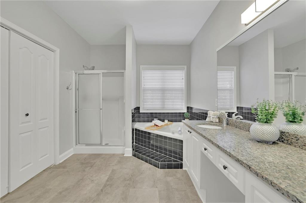 5696 Kilrush Court Mableton, GA 30126 - Photo 25 of 46 a spacious bathroom with a granite countertop sink a mirror and a bathtub
